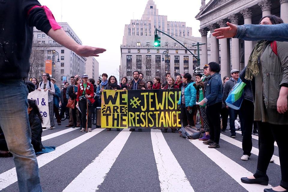 Protesters gather behind a sign saying We Are The Jewish Resistance