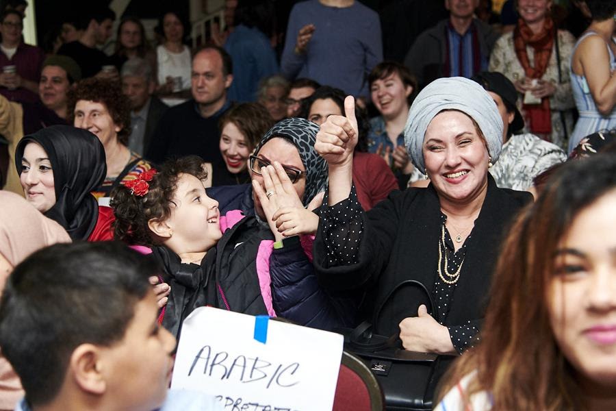 A group of people gather while one woman gives a thumbs up