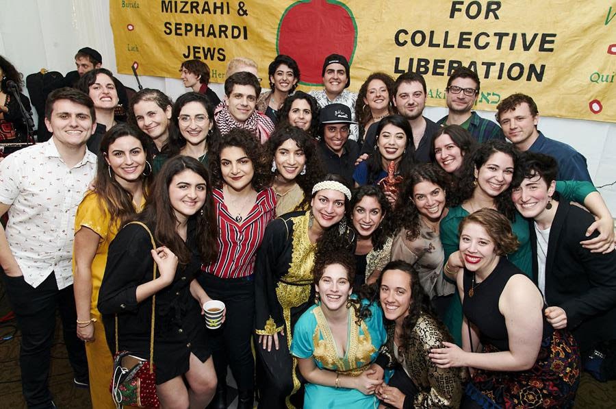 Several people gather in front of a banner for Mizrahi and Sephardi Jews
